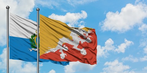 San Marino and Bhutan flag waving in the wind against white cloudy blue sky together. Diplomacy concept, international relations.