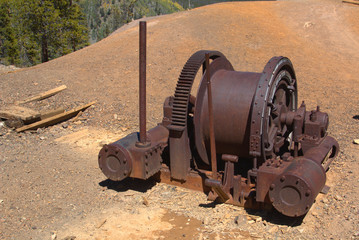 Abandoned winch sits becide a pile of mine tailings on a mountain mine in Colorado