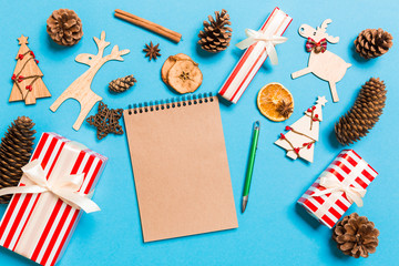 Obraz premium Top view of notebook on blue background made of Christmas decorations. New Year time concept