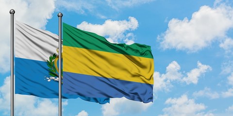 San Marino and Gabon flag waving in the wind against white cloudy blue sky together. Diplomacy concept, international relations.