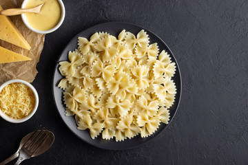Tasty appetizing cooked italian farfalle pasta (bow-tie or butterfly) in a plate. Above view with copy space. Black background.