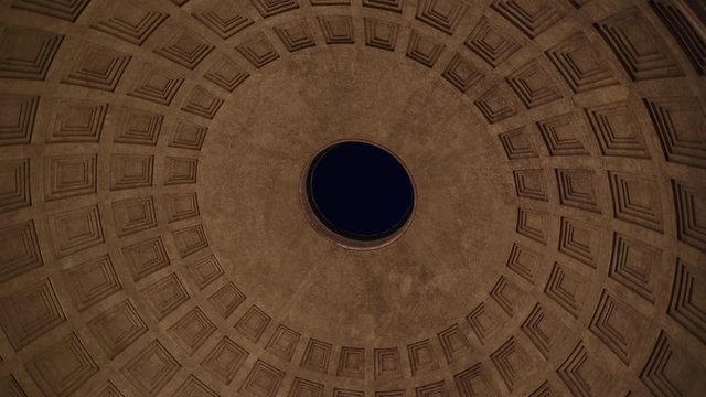 Inside Roman Pantheon at night, look up view with round motion, ancient concrete dome with hole in center in Rome, Italy