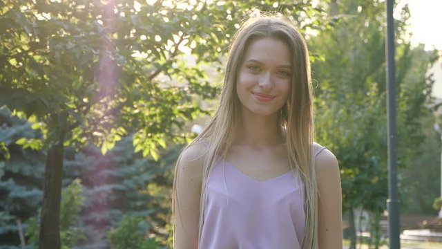 Beautiful young woman in park on sunny day, space for text. Slow motion effect