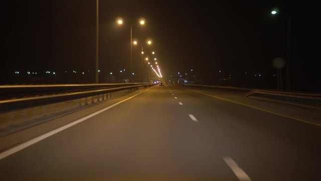 POV. Driving a car on a night highway, point of view. Street lights illuminate the track. On the other side of the road oncoming cars. Ultra HD stock footage.