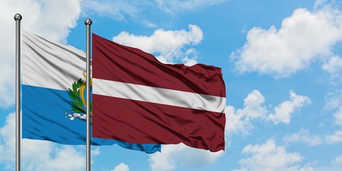 San Marino and Latvia flag waving in the wind against white cloudy blue sky together. Diplomacy concept, international relations.