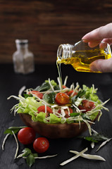 fresh vegetable salad on a wooden table in an eco-friendly dish, add olive oil to the salad, vegetarian natural food