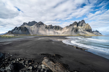 vestrahorn in southern Iceland, mirroring in calm water over black volcanic beach, landscape 