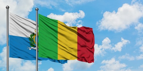 San Marino and Mali flag waving in the wind against white cloudy blue sky together. Diplomacy concept, international relations.