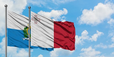 San Marino and Malta flag waving in the wind against white cloudy blue sky together. Diplomacy concept, international relations.