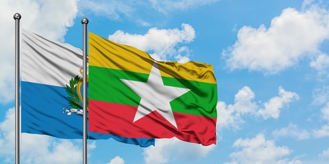 San Marino and Myanmar flag waving in the wind against white cloudy blue sky together. Diplomacy concept, international relations.