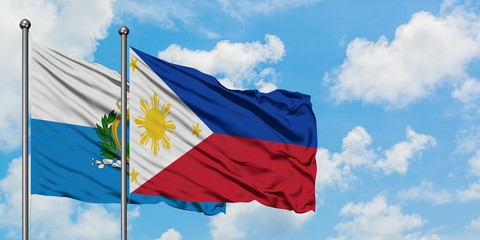 San Marino and Philippines flag waving in the wind against white cloudy blue sky together. Diplomacy concept, international relations.