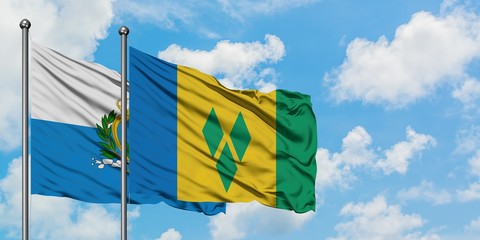 San Marino and Saint Vincent And The Grenadines flag waving in the wind against white cloudy blue...