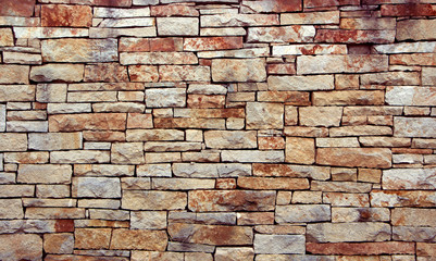 Antique red stone wall cobblestones with seamless masonry