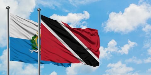 San Marino and Trinidad And Tobago flag waving in the wind against white cloudy blue sky together. Diplomacy concept, international relations.