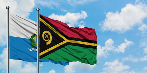 San Marino and Vanuatu flag waving in the wind against white cloudy blue sky together. Diplomacy concept, international relations.
