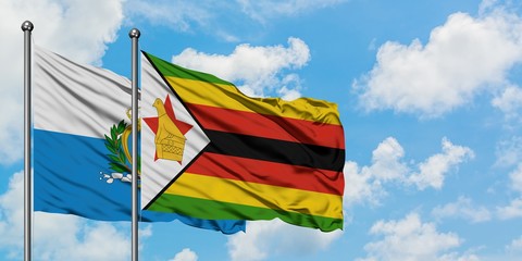 San Marino and Zimbabwe flag waving in the wind against white cloudy blue sky together. Diplomacy concept, international relations.