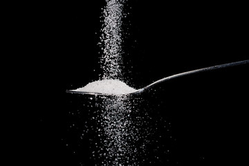 spoon of sugar on black background