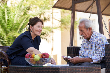 Professional helpful caregiver and a senior man during home visit