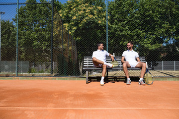 Tennis players sitting on a bench and talking during break