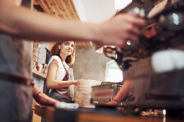 Process of making fresh drink. With machine. Two young cafe workers indoors. Conception of business and service