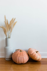 Two rustic pumpkins with dried grass in vase