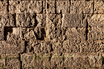 old grey rectangular stone wall with many rough edges