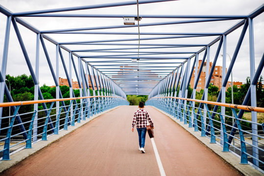 Gypsy boy with guitar walking across the bridge