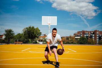 Man playing basketball on yellow court, dribbling