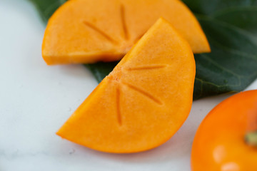 Macro of sliced persimmon fruit on marble background