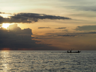 Naklejka na ściany i meble lonely small fishing boats on the open ocean against a background of storm clouds at sunset 
