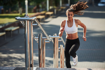 Sportive woman have fitness day and running in the city at daytime. Near the railings