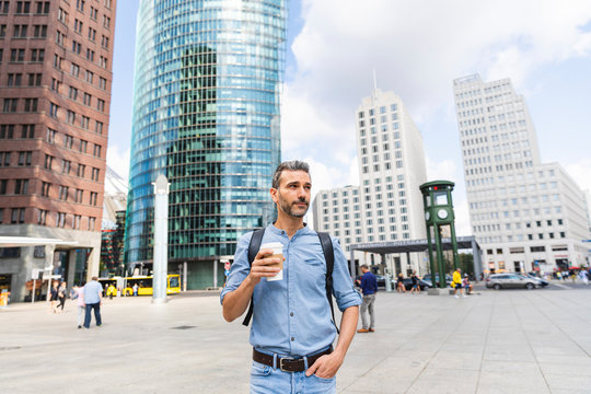 Man in the city holding a cup of coffee, Berlin, Germany