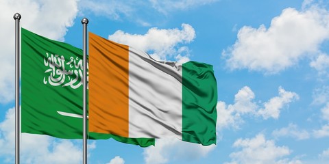 Saudi Arabia and Cote D'Ivoire flag waving in the wind against white cloudy blue sky together. Diplomacy concept, international relations.
