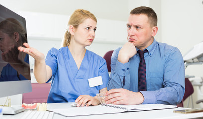 Fototapeta premium Female dentist explaining x-ray to frustrated male