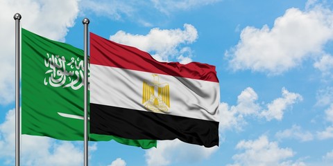 Saudi Arabia and Egypt flag waving in the wind against white cloudy blue sky together. Diplomacy concept, international relations.