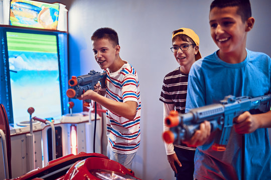 Teenage friends shooting with guns in an amusement arcade