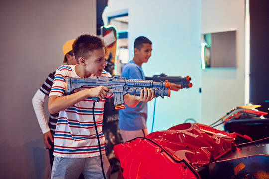 Teenage friends shooting with guns in an amusement arcade