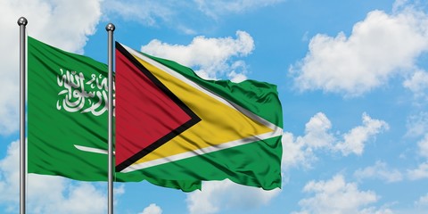 Saudi Arabia and Guyana flag waving in the wind against white cloudy blue sky together. Diplomacy concept, international relations.