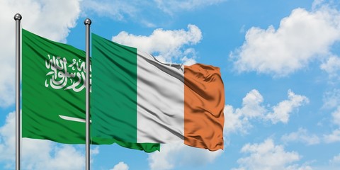 Saudi Arabia and Ireland flag waving in the wind against white cloudy blue sky together. Diplomacy...