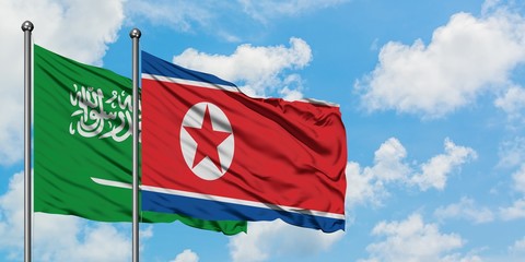 Saudi Arabia and North Korea flag waving in the wind against white cloudy blue sky together. Diplomacy concept, international relations.