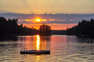 Beautiful fiery sunset on a lake with an island in Muskoka, Ontario.