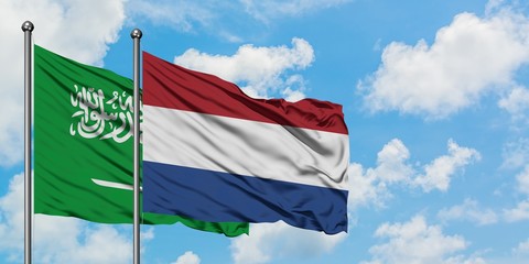 Saudi Arabia and Netherlands flag waving in the wind against white cloudy blue sky together. Diplomacy concept, international relations.