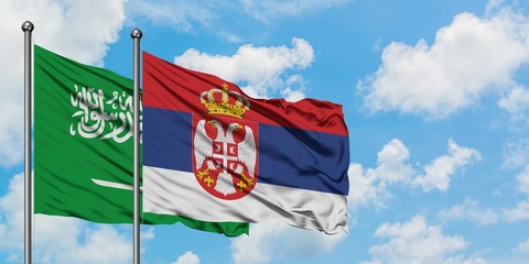 Saudi Arabia and Serbia flag waving in the wind against white cloudy blue sky together. Diplomacy concept, international relations.