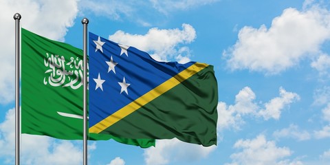 Saudi Arabia and Solomon Islands flag waving in the wind against white cloudy blue sky together. Diplomacy concept, international relations.