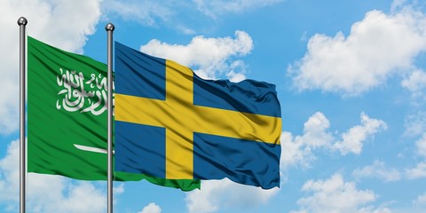 Saudi Arabia and Sweden flag waving in the wind against white cloudy blue sky together. Diplomacy concept, international relations.