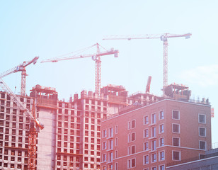 Fototapeta na wymiar Multiple industrial cranes constructing buildings background
