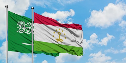 Saudi Arabia and Tajikistan flag waving in the wind against white cloudy blue sky together. Diplomacy concept, international relations.