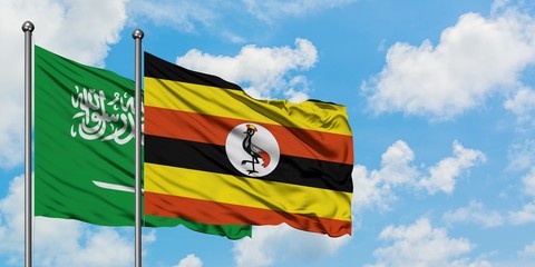 Saudi Arabia and Uganda flag waving in the wind against white cloudy blue sky together. Diplomacy concept, international relations.