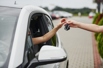 Taking keys of the car. Two people. Girl sitting in her brand new automobile