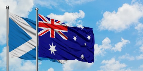Scotland and Australia flag waving in the wind against white cloudy blue sky together. Diplomacy concept, international relations.